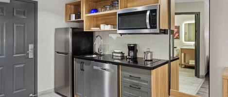 A modern kitchen with stainless steel appliances, wooden shelves, and a large mirror.
