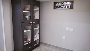 Una habitación con un armario de madera oscura, un letrero en la pared que dice "LENDING LOCKER" y un suelo de baldosas.