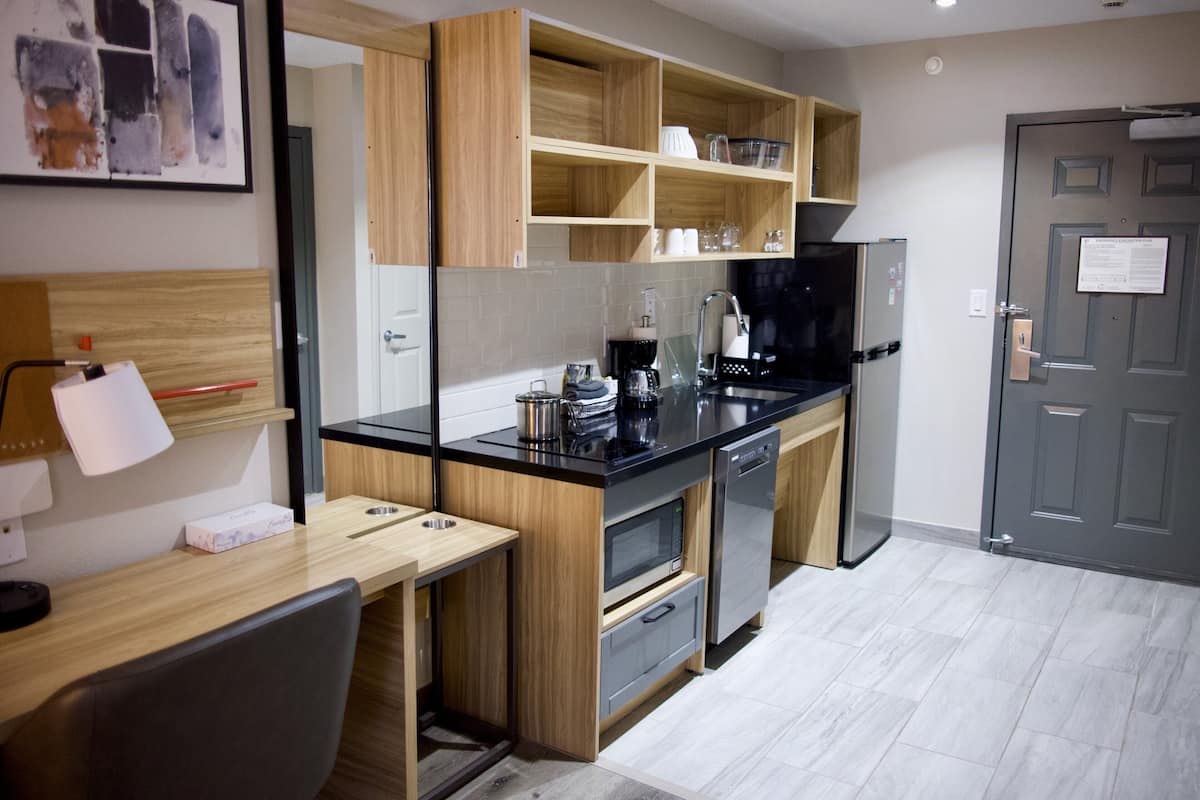 A compact kitchen with wooden cabinets, a black countertop, and a built-in oven.