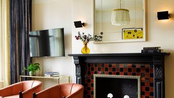 Una sala de estar con chimenea, televisor y un espejo grande.
