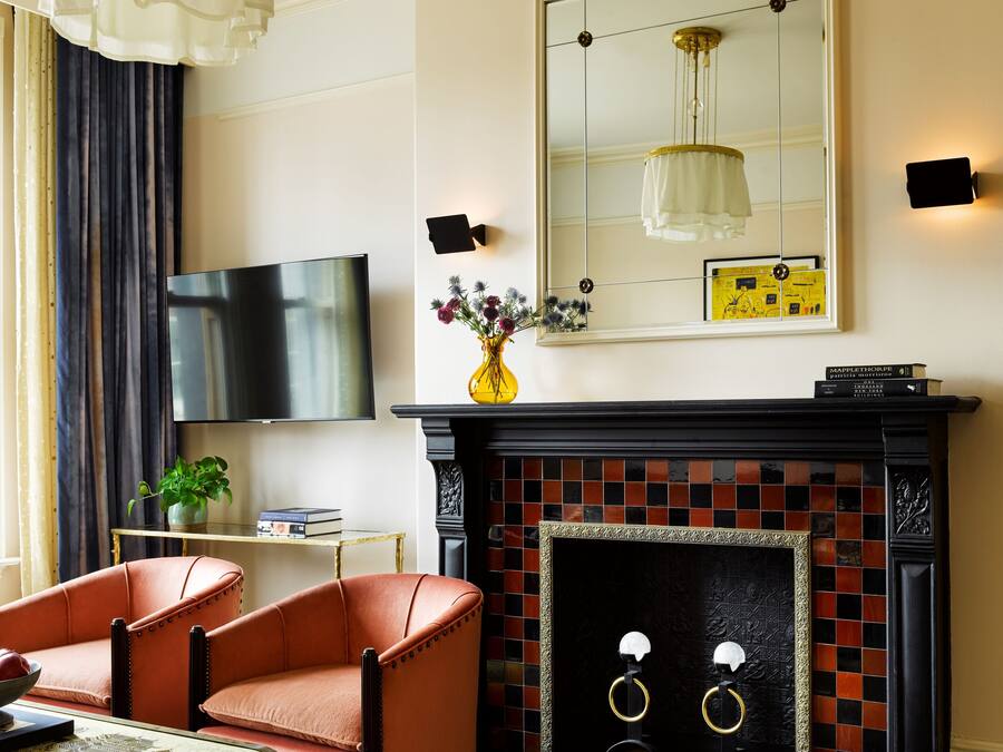 Una sala de estar con chimenea, televisor y un espejo grande.
