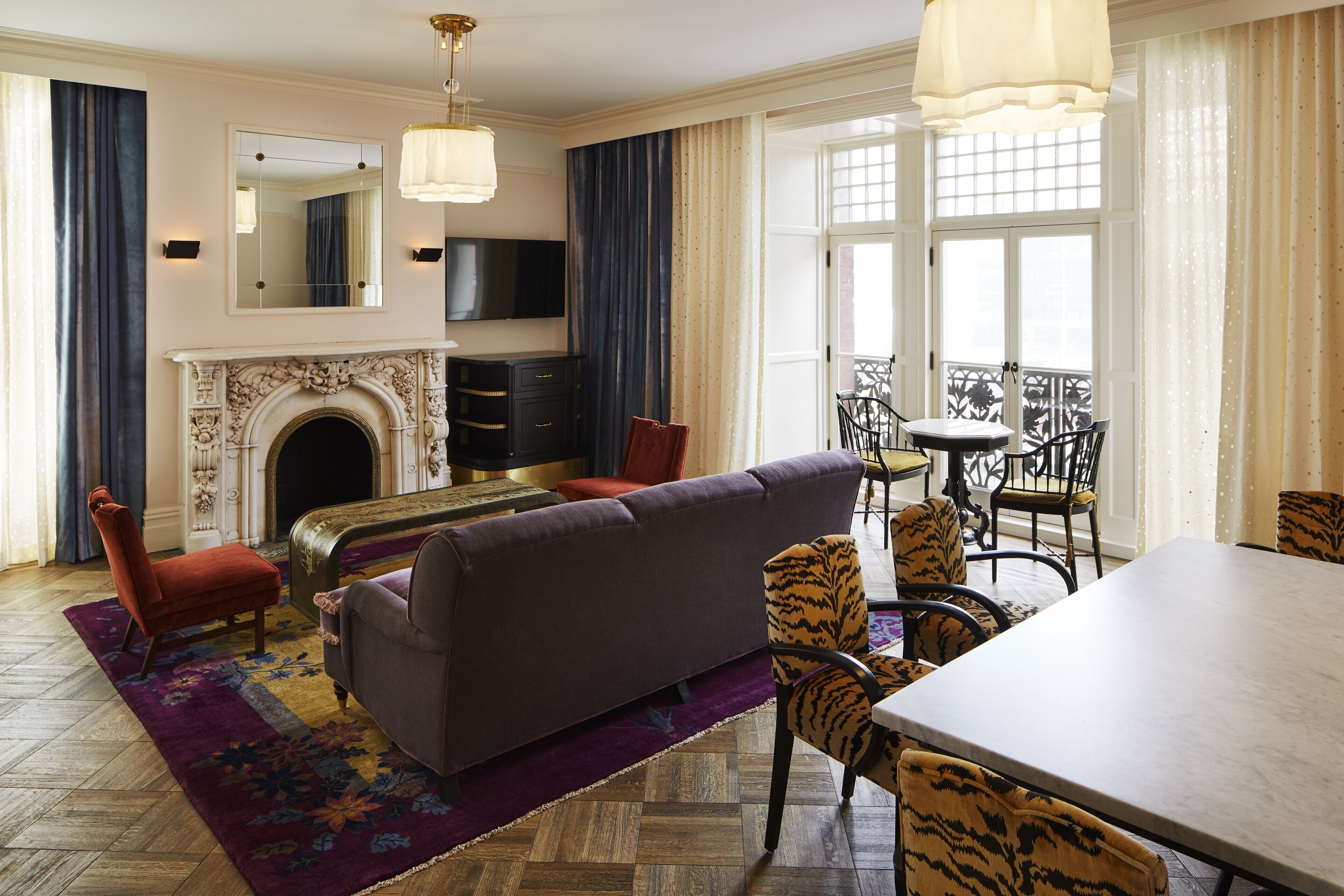 A spacious living room with a fireplace, a sofa, a dining table, and chairs.
