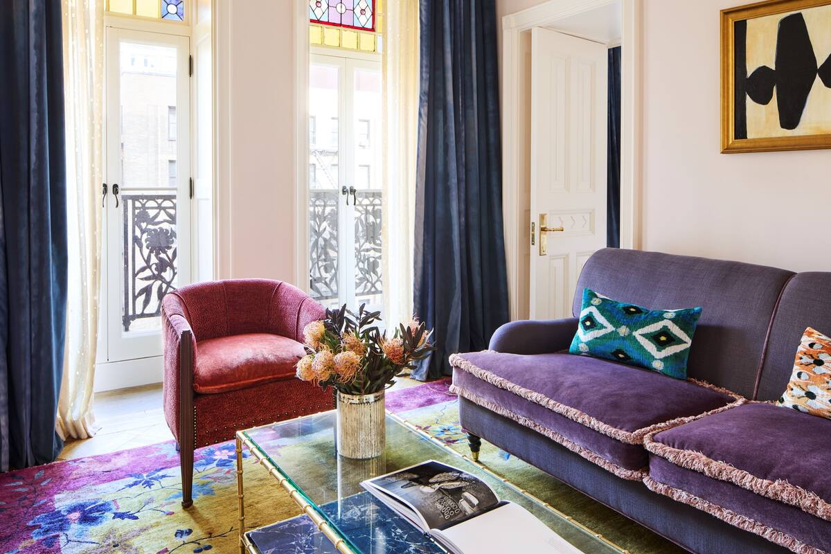 A living room with a red armchair, a purple sofa, and a glass coffee table.