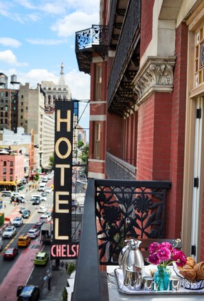 Un letrero de hotel, una vista de la calle y una bandeja de desayuno con flores y pasteles.