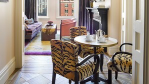A hotel room with a dining area, a sofa set, a fireplace, and a view of the cityscape. - The Hotel Chelsea (New York)