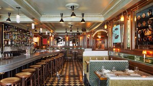 A bar area with a checkered floor, multiple stools, and a long counter with bar stools. - The Hotel Chelsea (New York)