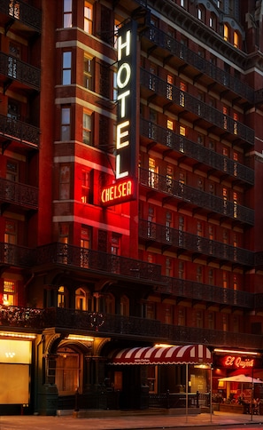 Un hotel con un llamativo letrero que dice 'HOTEL CHELSEA', varios balcones y un estilo arquitectónico clásico.