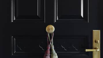 A black door with a brass doorknob, a brass handle, and a decorative tassel.
