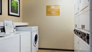 Een wasserette met wasmachines en drogers, een waarschuwingsbord en een bordje dat aangeeft dat wassen en drogen gratis is.