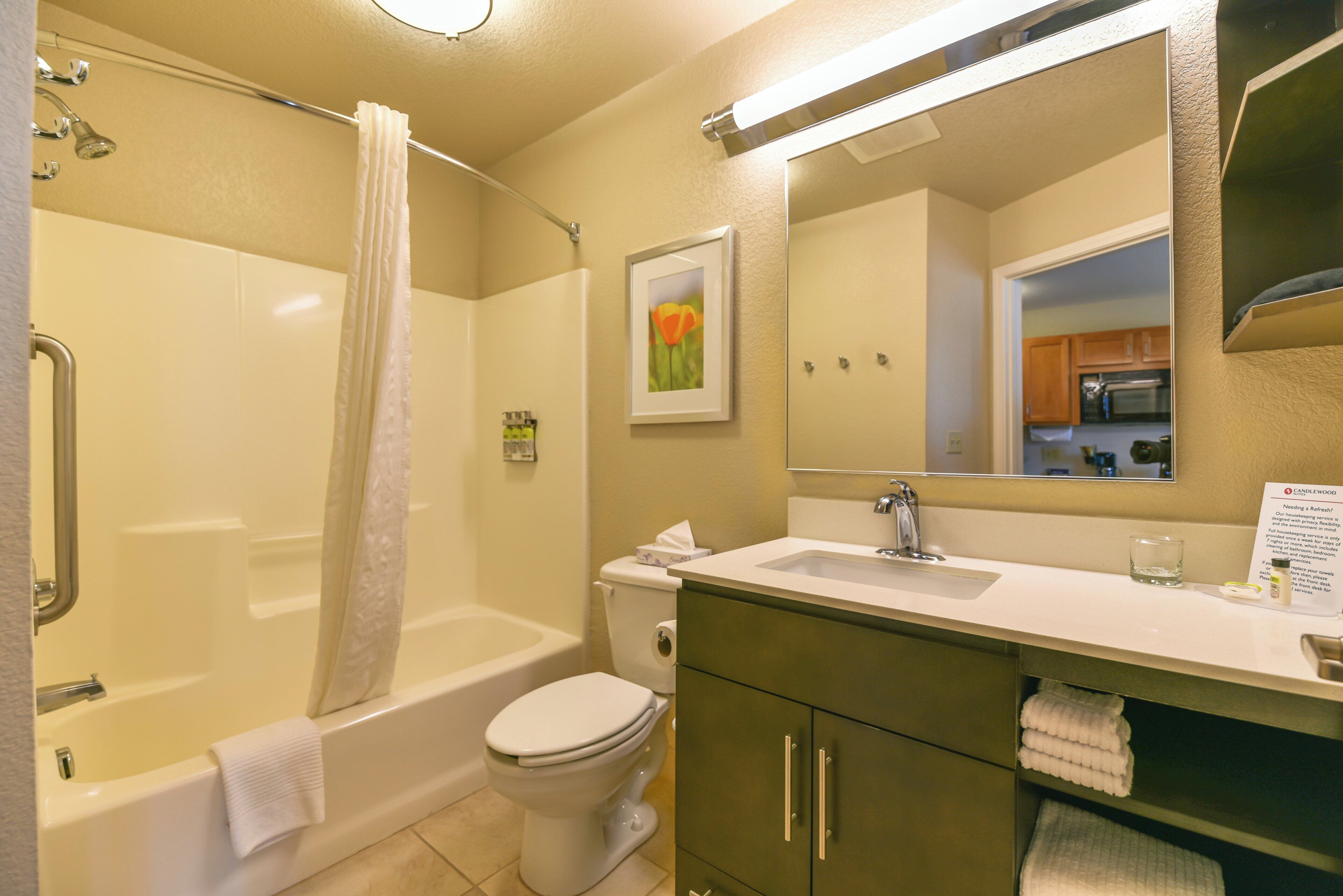 A bathroom with a bathtub, toilet, sink, and a large mirror.