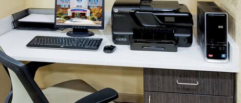 A home office setup with a desktop computer, printer, and keyboard.