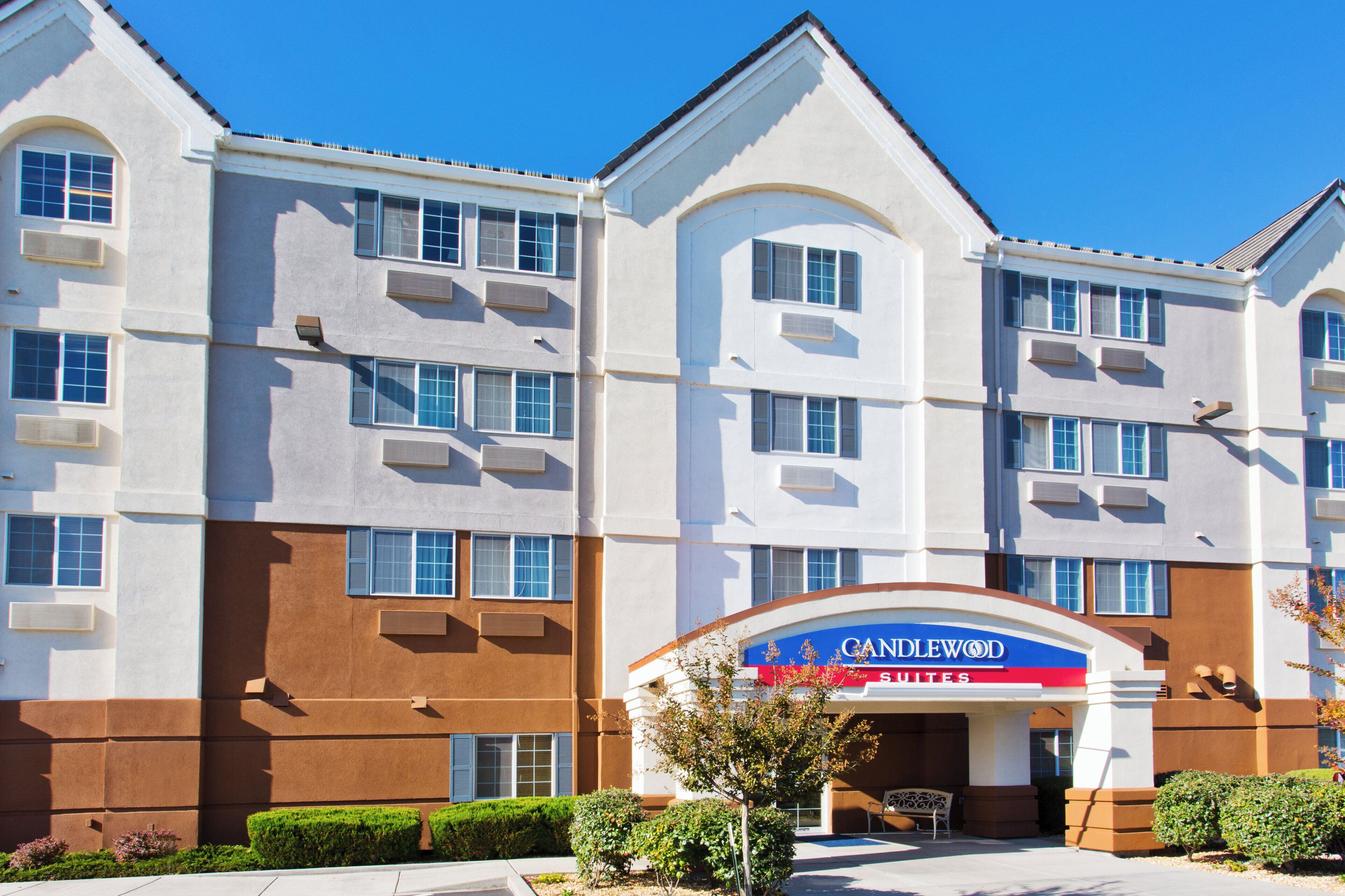 A multi-story hotel with a prominent entrance, air conditioning units, and a clear sky.