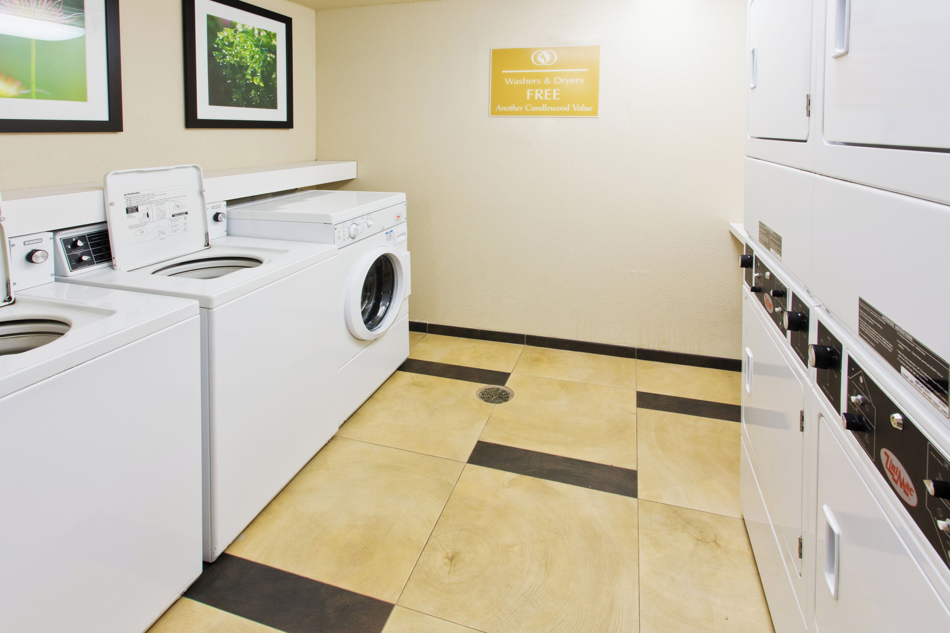 Une buanderie équipée d’un lave-linge, d’un sèche-linge et d’un panneau indiquant que les lave-linge et les sèche-linge sont à disposition gratuitement.