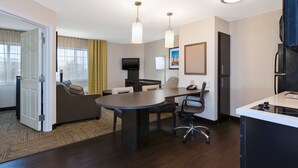 A modern hotel room with a dining area, a sofa, a TV, and a kitchen counter. - Candlewood Suites Polaris by IHG (Columbus)