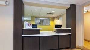 A reception desk with a computer monitor, a glass partition, and a wall-mounted security camera. - Candlewood Suites Polaris by IHG (Columbus)