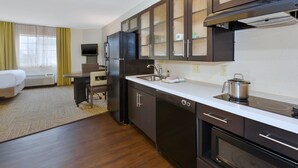 A compact hotel kitchen with a refrigerator, stove, sink, and microwave. - Candlewood Suites Polaris by IHG (Columbus)