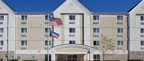 A multi-story hotel with a symmetrical facade, a central entrance, and a flagpole with the American flag.