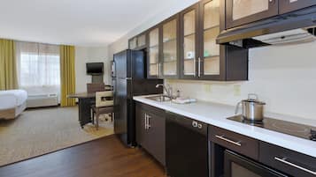 Une petite cuisine d’hôtel équipée d’un réfrigérateur, d’une cuisinière, d’un four à micro-ondes et d’un évier.