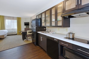 A compact hotel kitchen with a refrigerator, stove, microwave, and a sink. - Candlewood Suites Polaris by IHG (Columbus)