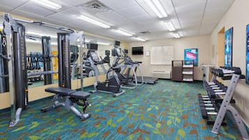 Un gimnasio con diversos equipos de ejercicio, como cintas de correr y máquinas de pesas.