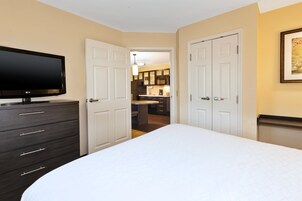 Um quarto com uma cama, cômoda, televisão e uma porta para um banheiro.