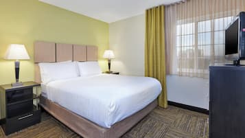 A hotel room with a bed, two bedside lamps, a TV, a desk, and a chair.
