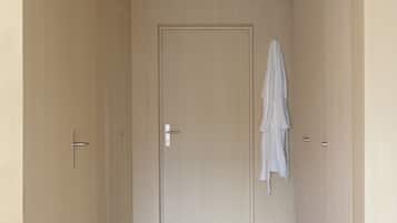 Un couloir avec une porte en bois, une serviette accrochée au mur et un plancher de couleur claire.