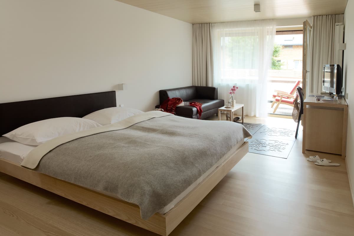 Una habitación de hotel moderna con una cama grande, un escritorio, una silla y un televisor.