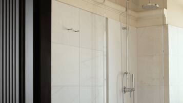 Een moderne badkamer met een glazen douchecabine, witte betegelde wanden en een zichtbaar deurklink.