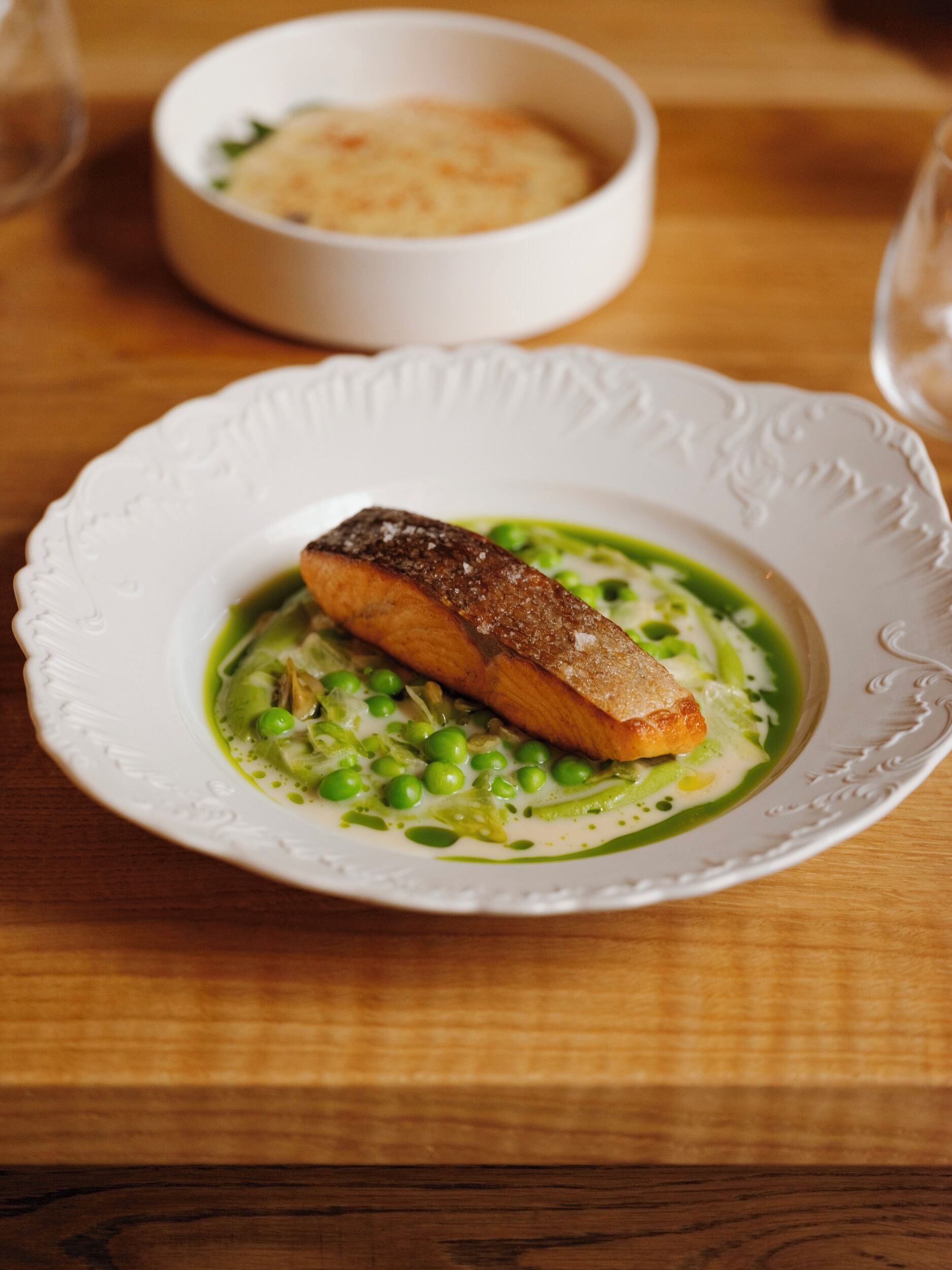 A plate of food with a piece of fish and peas on a white plate.