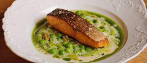 A plate of food with a piece of fish and peas on a white plate.