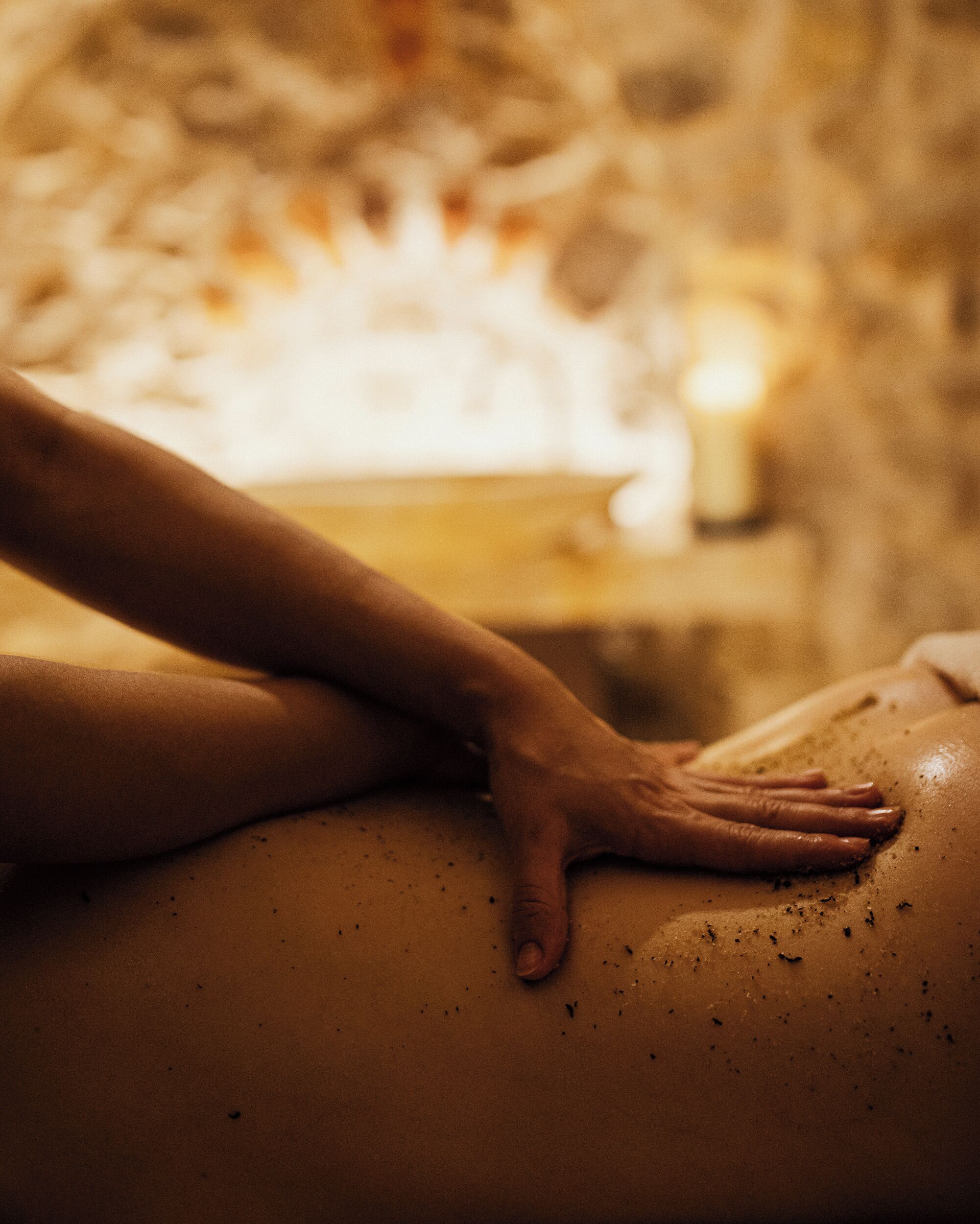 Una sesión de masoterapia en una habitación con poca luz y pared de piedra de fondo.