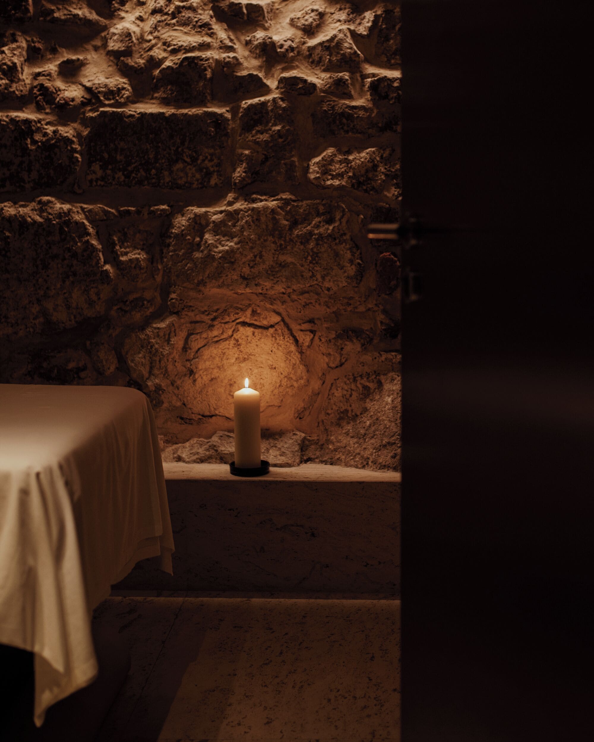 A candlelit alcove with a stone wall and a table.