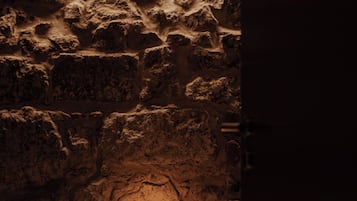 A candlelit alcove with a stone wall and a table.