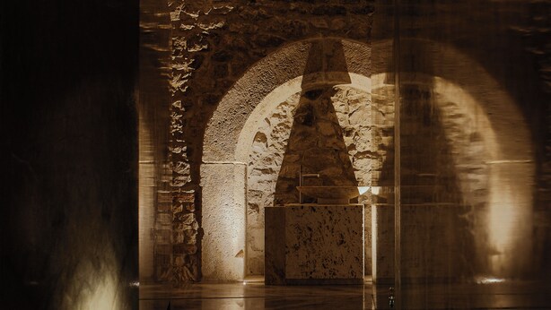 Un interior con arcos de piedra y suelo reflectante.