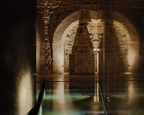 Ein Innenraum mit Steinbögen und einem spiegelnden Boden.