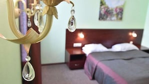 A hotel room with a bed, a nightstand, and a wall-mounted lamp. - Sesame (Riga)