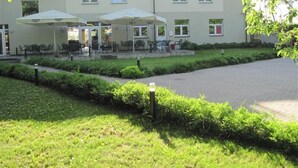 A building with a patio area featuring outdoor seating and umbrellas. - Sesame (Riga)