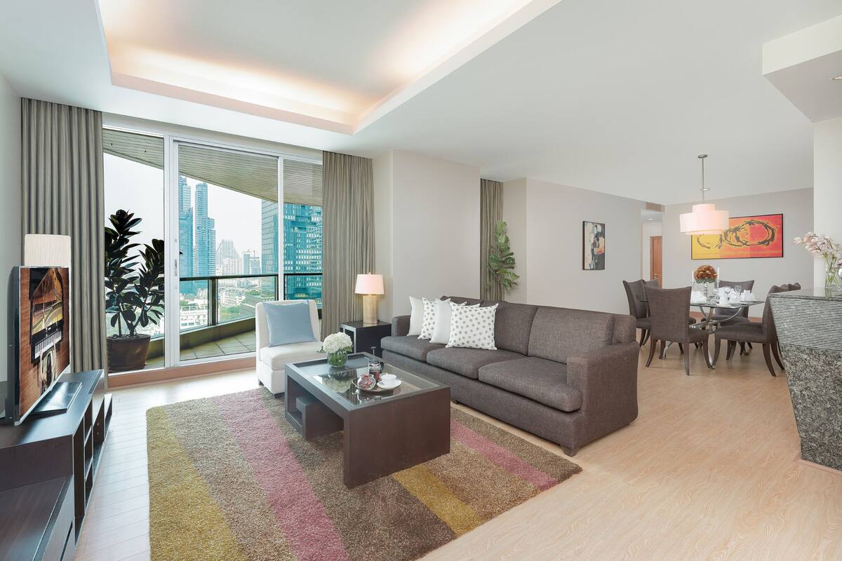 Ein modernes Wohnzimmer mit Sofa, Couchtisch und einem Essbereich mit Stühlen und Tisch.