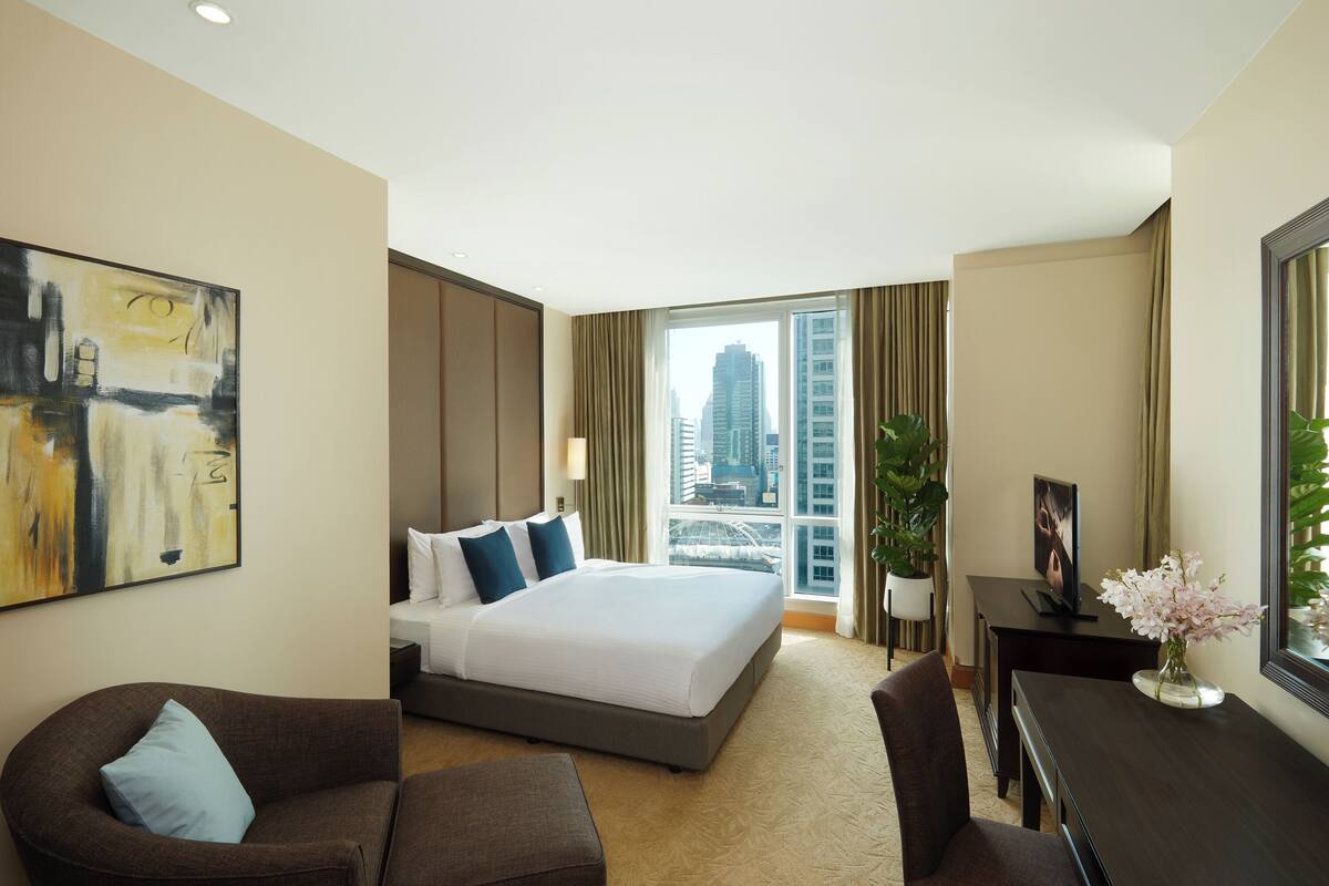 Ein Hotelzimmer mit einem großen Bett, einem Schreibtisch, einem Sessel, einer Couch und einem Bild an der Wand.