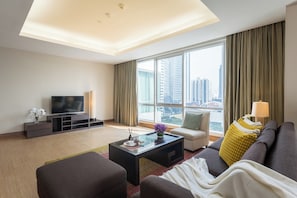 A modern living room with a flat-screen TV, a sofa, a coffee table, and a large window offering a city view. - Ascott Sathorn Bangkok (Bangkok)