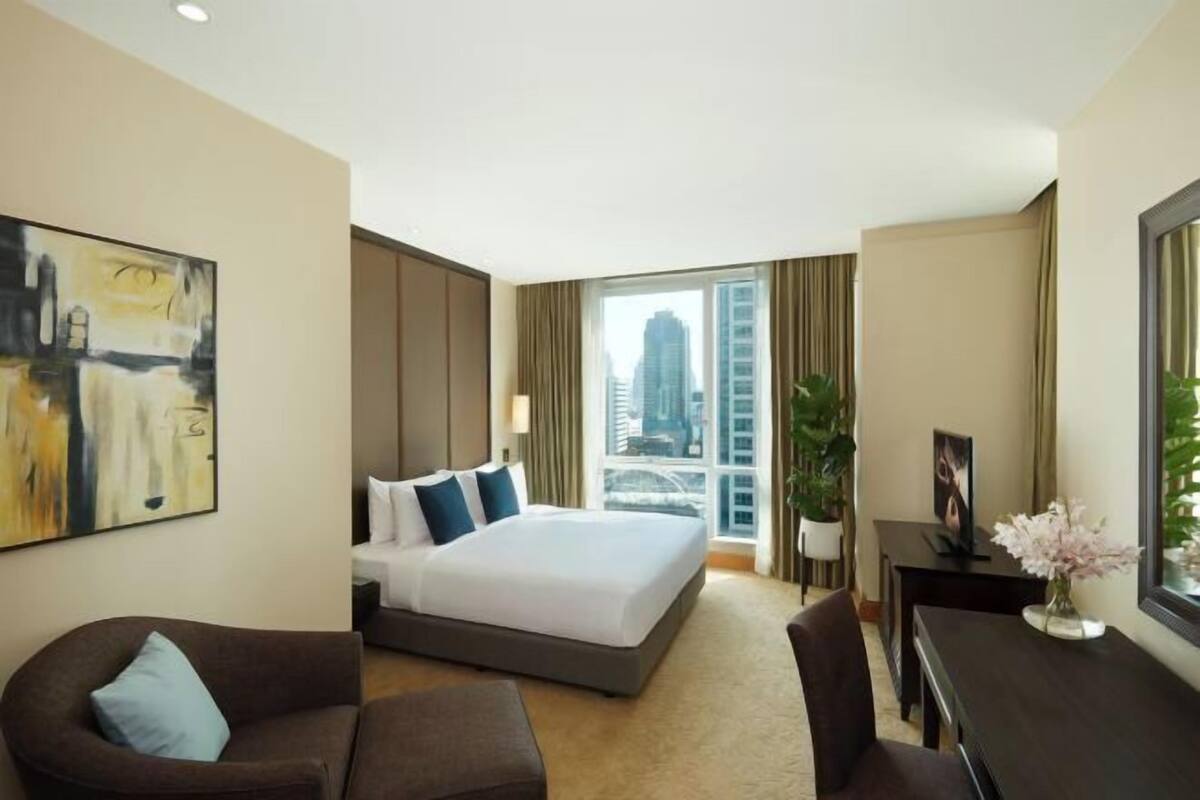 Ein Hotelzimmer mit einem großen Bett, einem Schreibtisch, einem Sessel, einer Couch und einem Bild an der Wand.