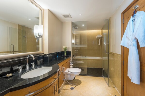 Un baño moderno con ducha envuelta en cristal, un lavabo blanco y un mueble de tocador de madera.