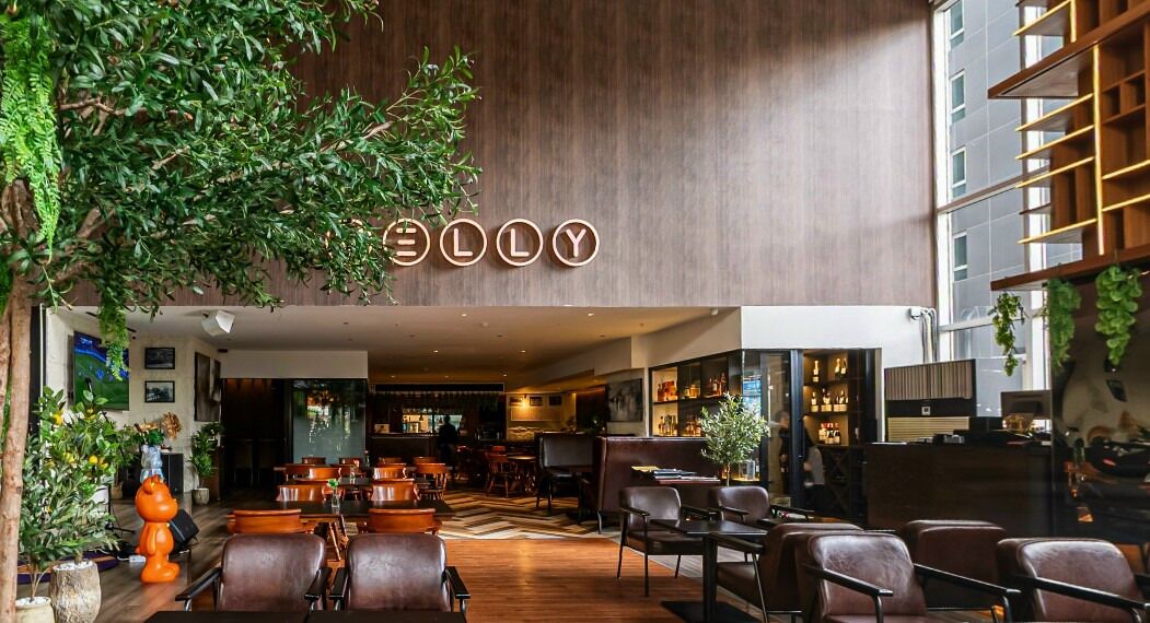 A modern interior with a bar area, seating, and a visible sign with the name 'ELLY'.