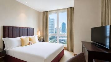 A hotel room with a large bed, a television, and a view of the cityscape.