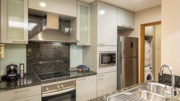 A modern kitchen with a stainless steel range hood, built-in microwave, and a double sink.