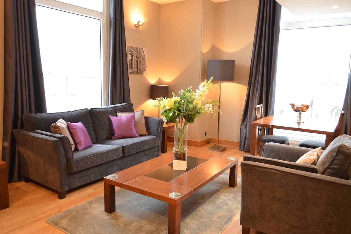A modern living room with a sofa, a coffee table, and a vase of flowers.