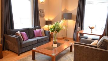 Een moderne woonkamer met een bank, een bijzettafeltje en een vaas met bloemen.