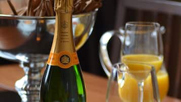 Une bouteille de champagne Veuve Clicquot, un panier de croissants et une carafe de jus d’orange sur une table.