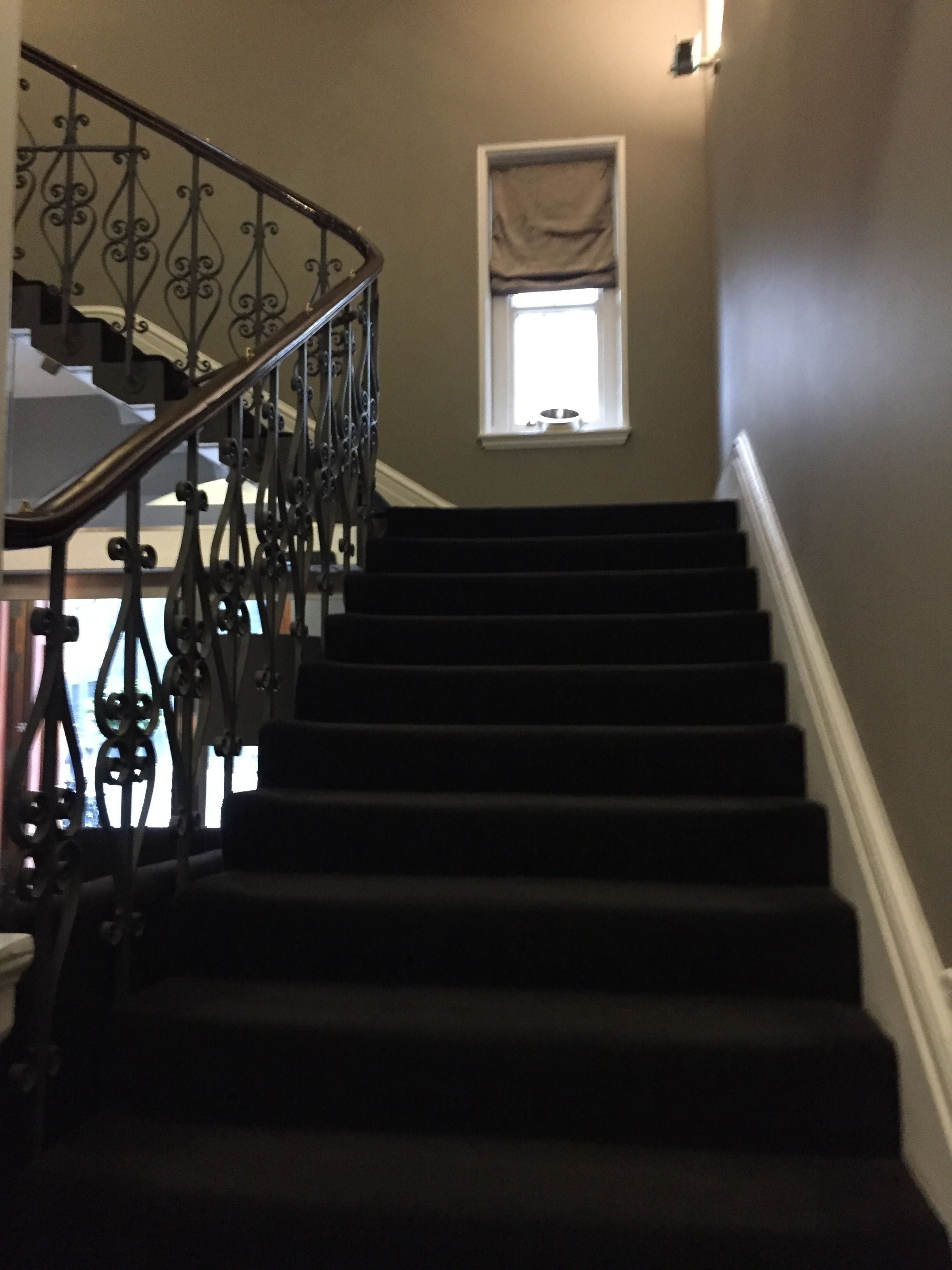 A staircase with a wrought iron railing leading to a landing.